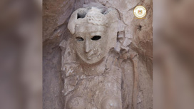 Погребальная маска изображает женщину с улыбкой на лице.